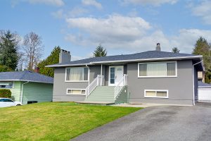 Older grey home in average neighborhood with asphalt roof. 