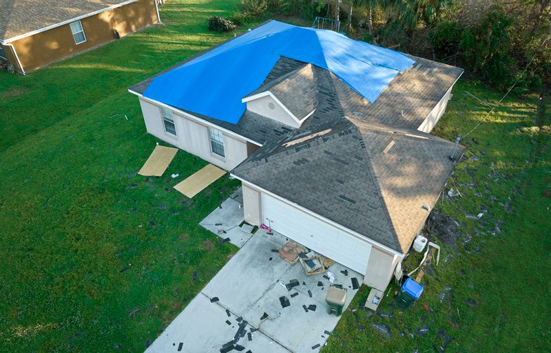 top-view-of-leaking-house-roof-covered | Anderson Roofing & Home Improvement LLC Damaged roof on a residential home after a severe storm.