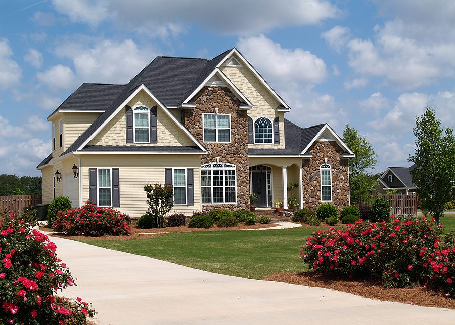 Two story tan and brick home with a new roof. 